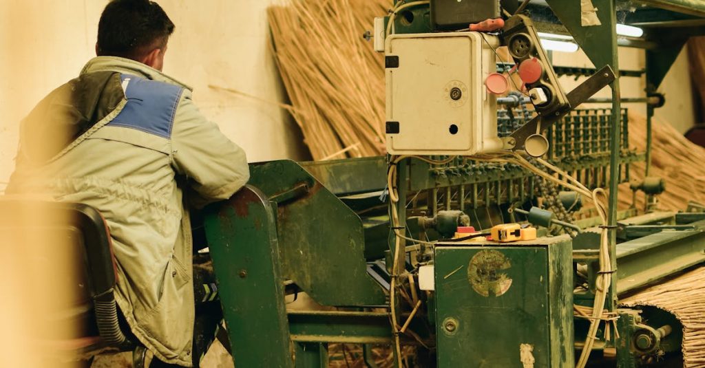 Man operating heavy machinery in an indoor industrial agricultural setting.