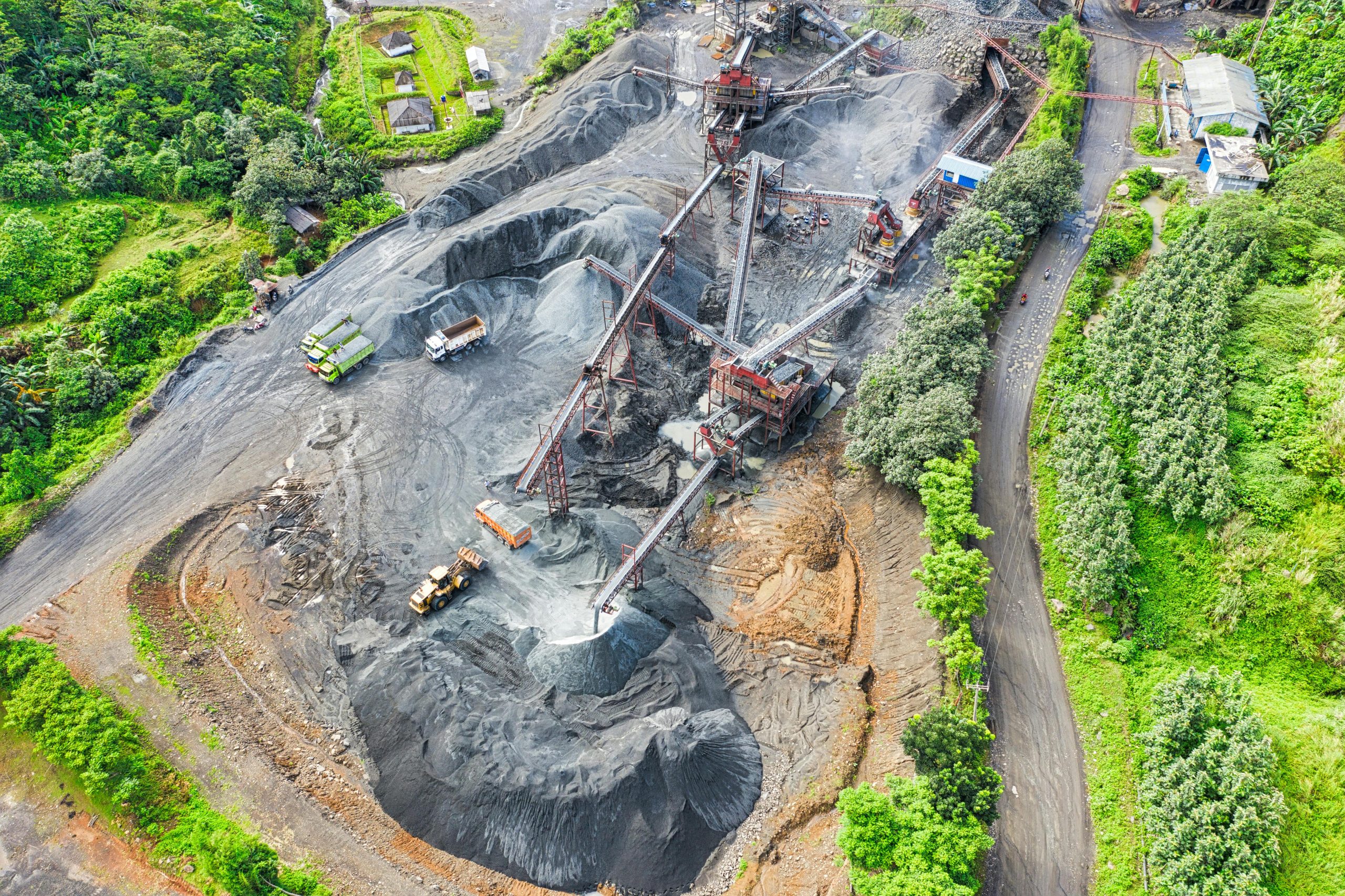 Aerial shot of a mining site surrounded by greenery, showcasing industrial activity.